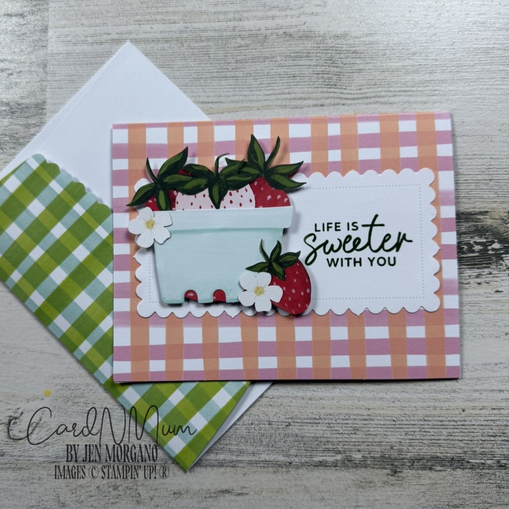 A handmade card featuring a basket of strawberries with the text 'LIFE IS SWEETER WITH YOU' on a pink and white checkered background, accompanied by a green checkered envelope.
