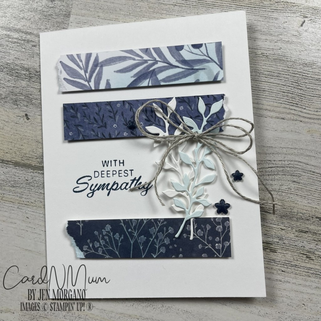 A handmade sympathy card featuring layered blue and purple patterned paper strips, delicate foliage embellishments, and twine.