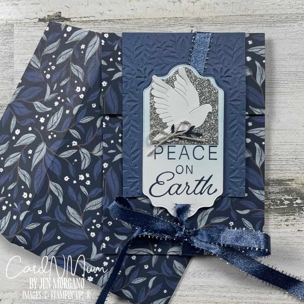 A handmade card featuring a dove, the words 'PEACE ON EARTH,' and a decorative background with blue leaves and floral patterns.