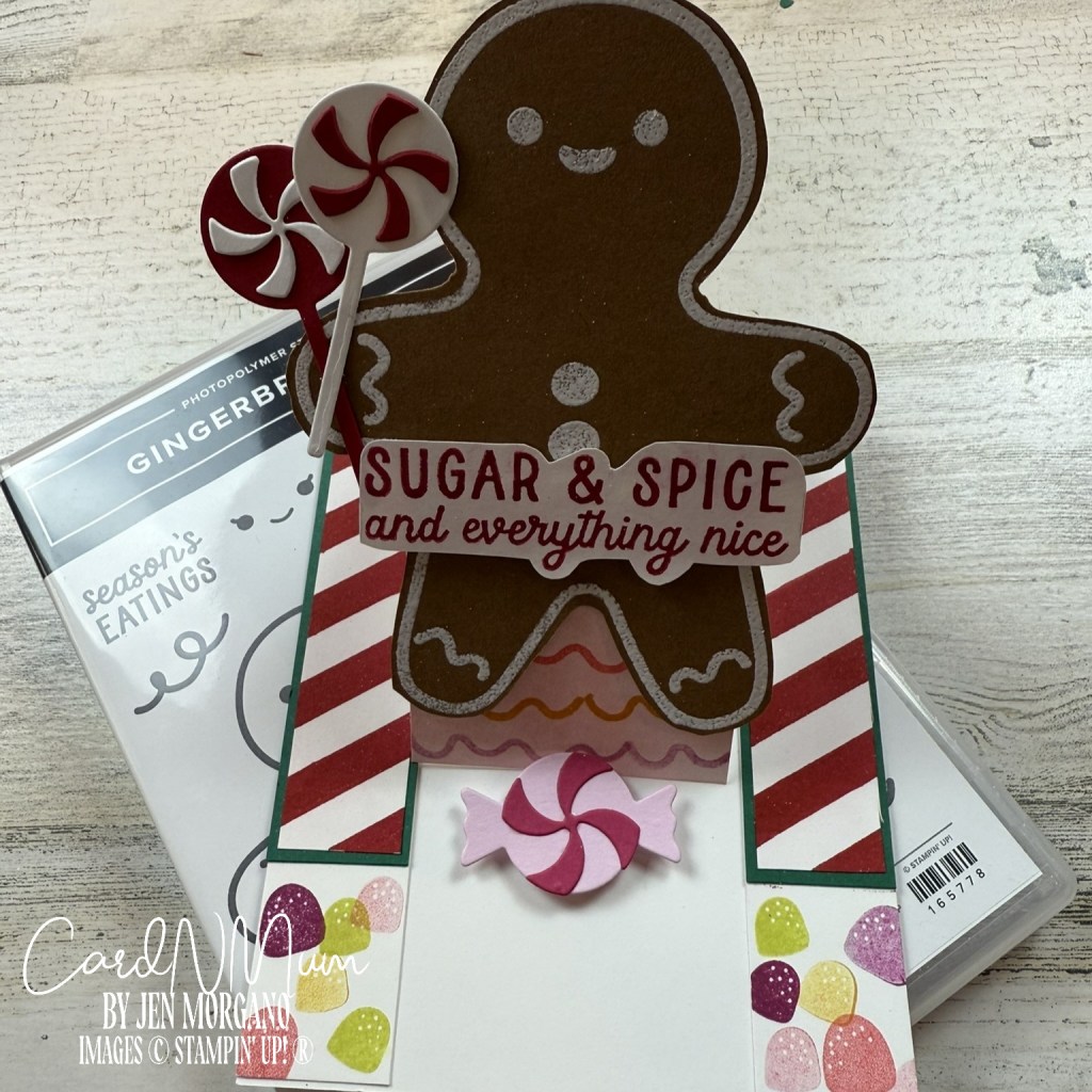 A pop-up card featuring a gingerbread man holding lollipops and a sentiment that reads 'SUGAR & SPICE and everything nice,' with decorated candy elements and a stamp set package in the background.