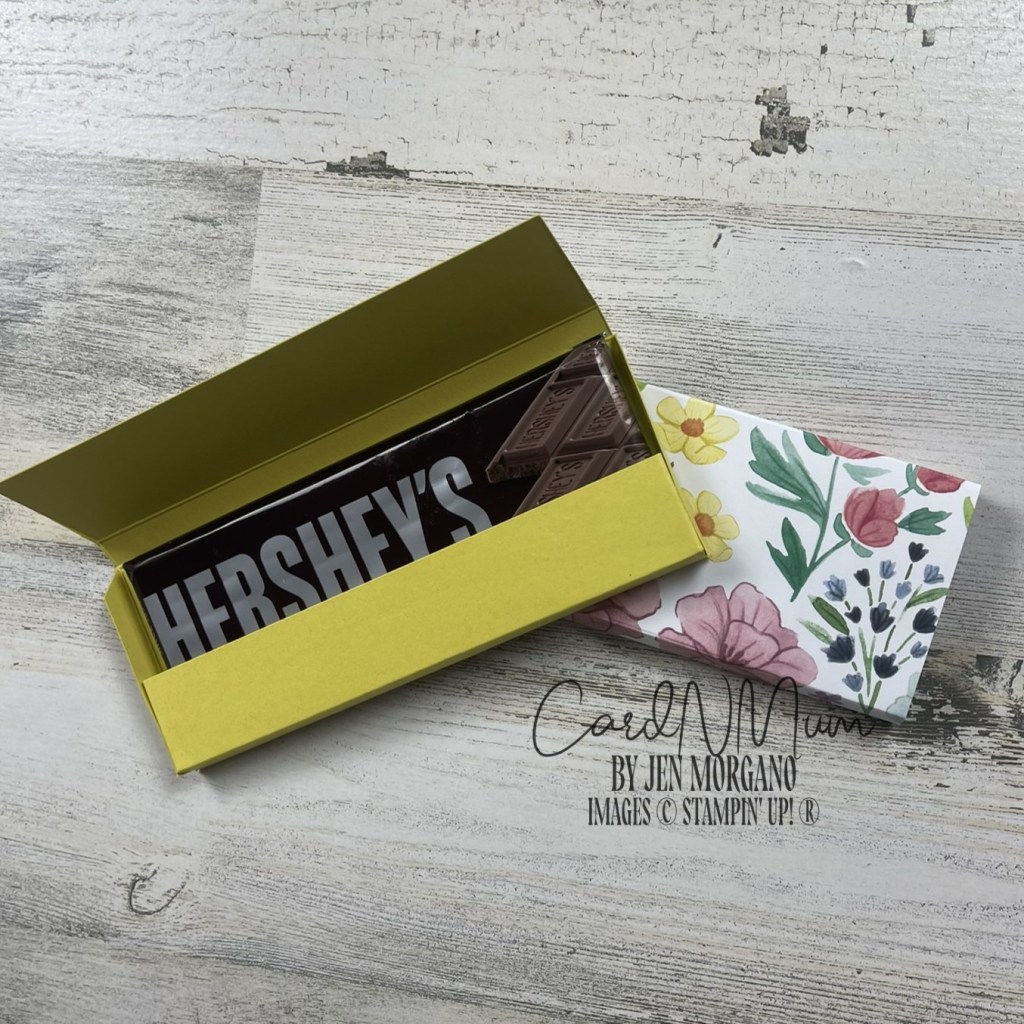 A yellow box with a partially opened lid containing a Hershey's chocolate bar, alongside a floral-patterned wrapper.