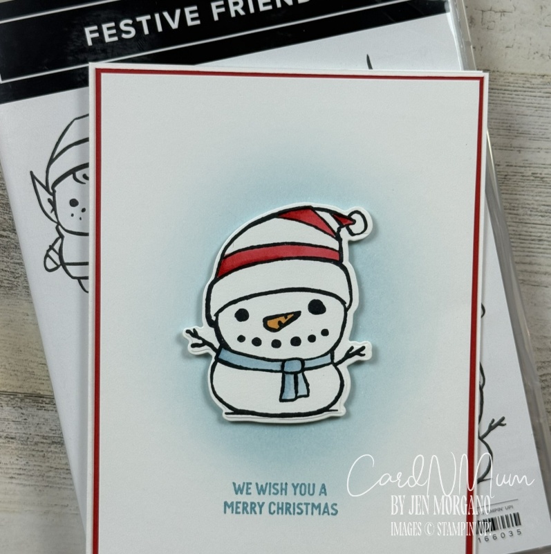 A cheerful snowman wearing a red and white striped hat and a blue scarf, with the text 'We wish you a Merry Christmas' below it. The snowman is placed on a white card with a light blue background.