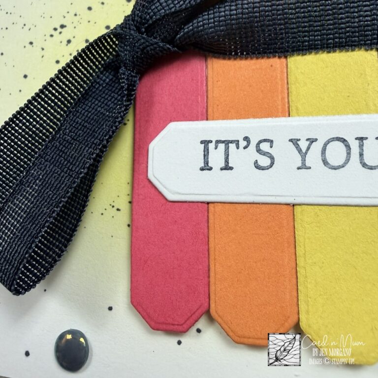 Close-up of a handmade Stampin’ Up! birthday card featuring layered cardstock strips in bold colors with a dark blue ribbon bow and stamped sentiment label.